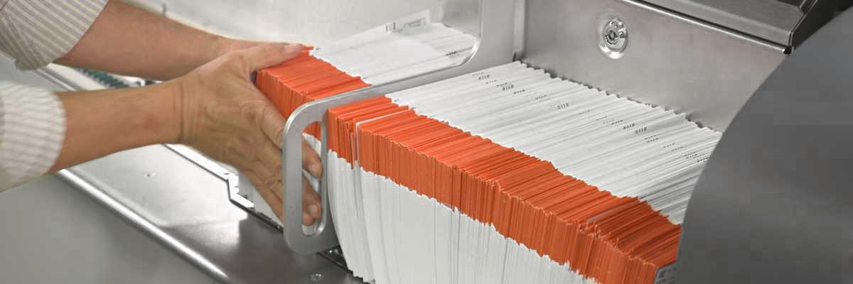 Vote-by-mail ballots processed and stacked in machine.